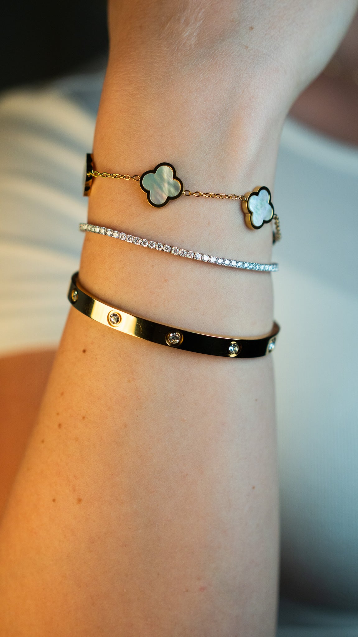 Носена комбинация от гривни CHÉRI – AMOUR гривна с 18K златно покритие, iced out гривна с цирконий и Pearl Clover модел; елегантен, водоустойчив стил за всеки повод