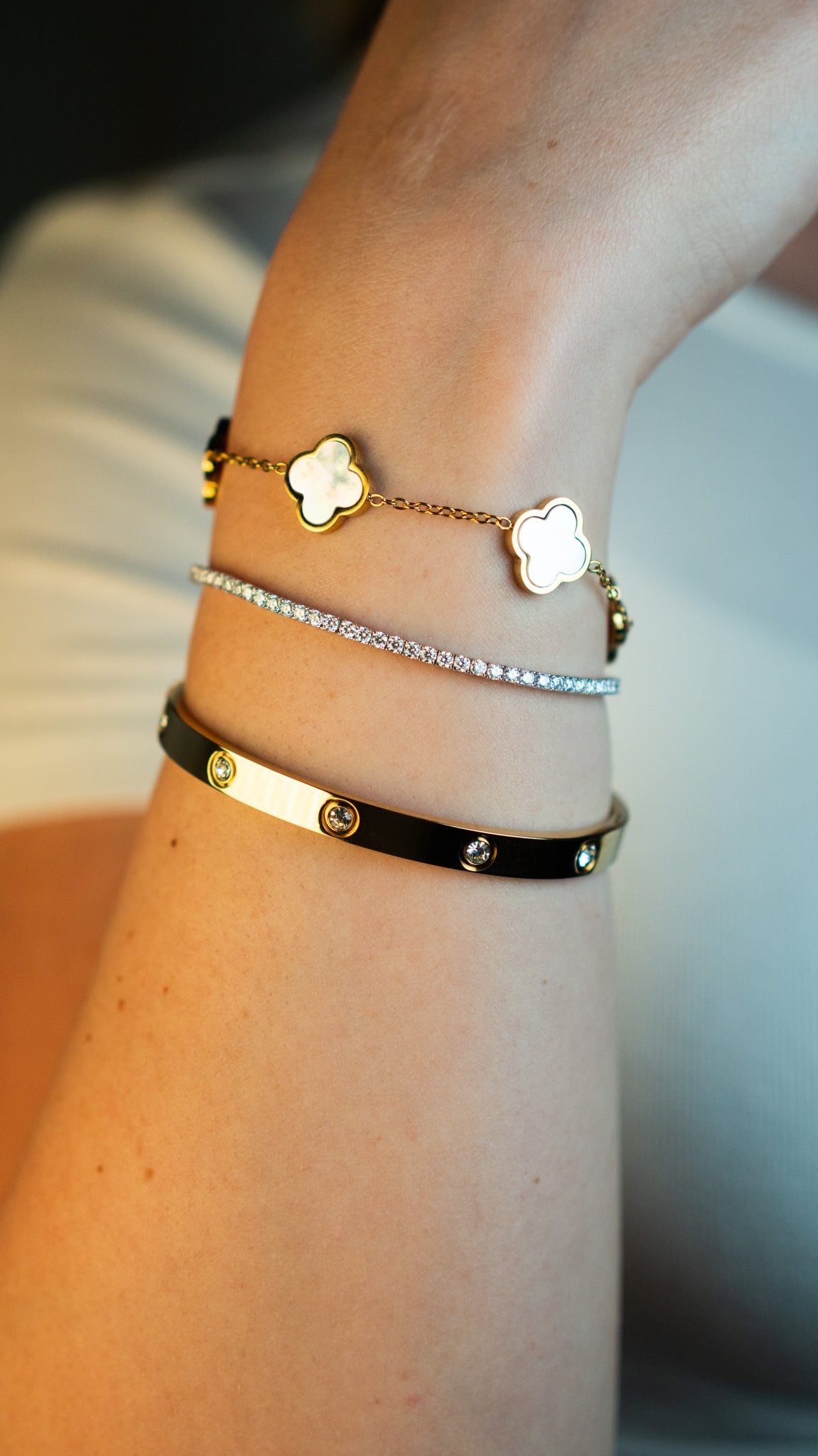 Три дамски гривни с четирилистна детелина в различни цветове от CHÉRI Jewelry, носени на ръка – стилна комбинация и вдъхновение за подарък.