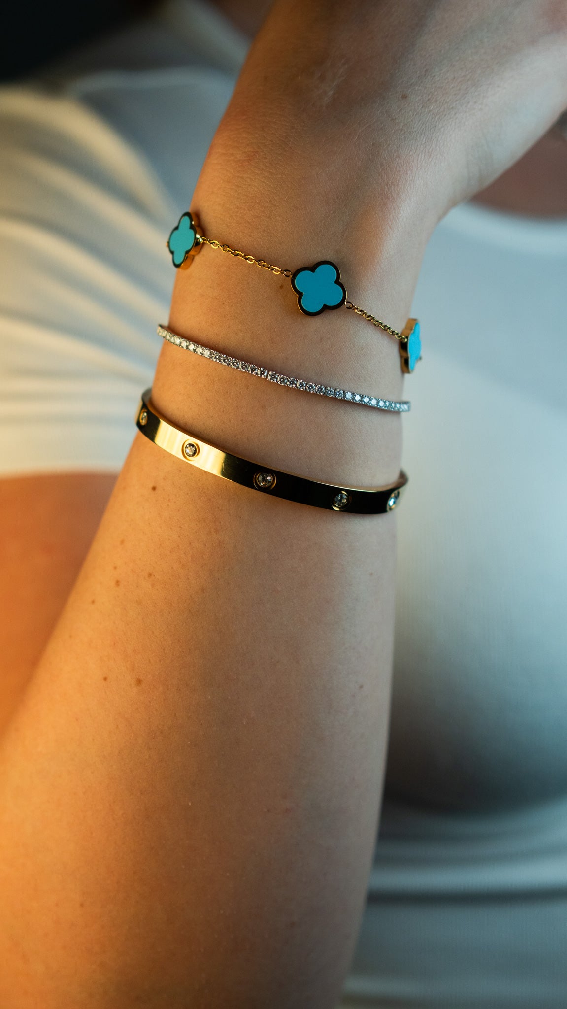 Дамска синя гривна с четирилистна детелина от CHÉRI Jewelry, носена в комбинация с други цветове – стилен и елегантен комплект бижута.